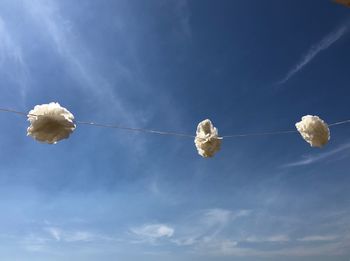 Low angle view of white lanterns hanging against blue sky