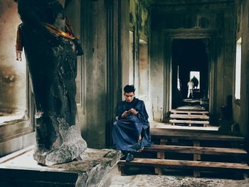 Full length of man sitting on seat in building