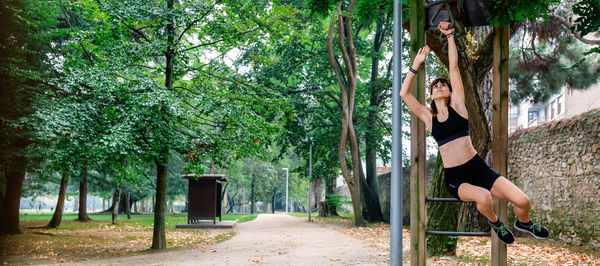 Woman exercising against trees in park