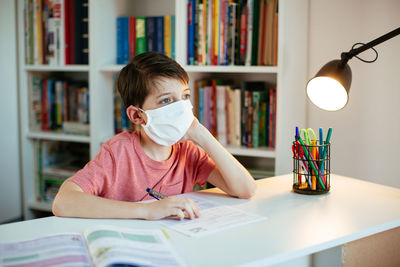 Boys wearing flu mask while studying at home