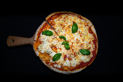 A tasty traditional margarita pizza topped with fresh basil and served on a wooden plate