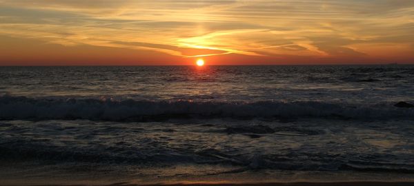 Scenic view of sea against dramatic sky during sunset