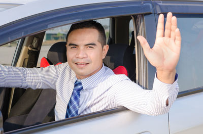 Businessman waving hand while driving car