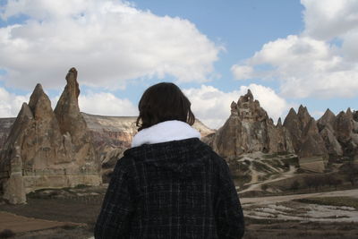 Rear view of man looking at mountain range against cloudy sky