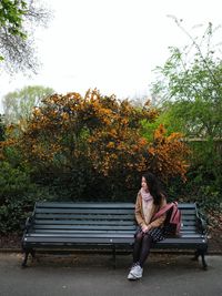 Full length of woman sitting on bench in park