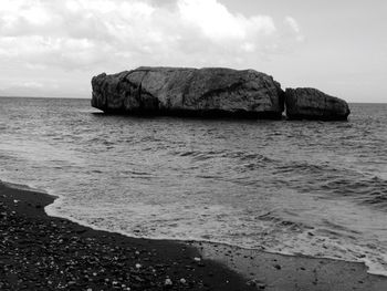 Rock formation in sea against sky