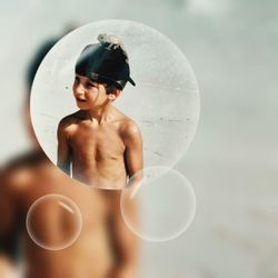 Full length of shirtless boy standing against blurred background