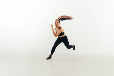 Full length of woman dancing against white background