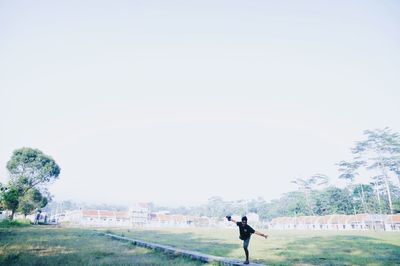 Rear view of man standing on field against clear sky