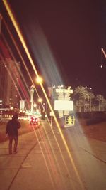 Blurred motion of man walking on illuminated street at night