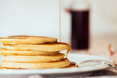 Close-up of maple syrup falling on fresh pancakes