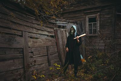 A guy in a gas mask is standing near an abandoned house