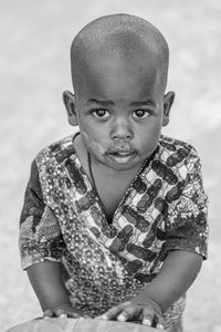 Portrait of young man sitting against wall