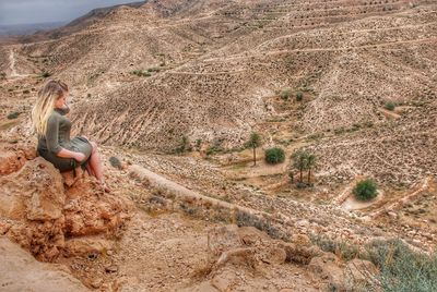 Side view of woman sitting on land