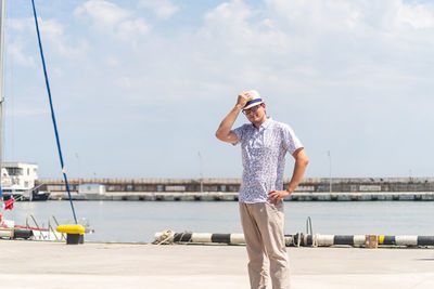 Summer travel. male tourist in straw hat walking in the sea port, boats and yachts on the background