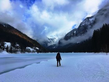 Rear view of person walking on snow covered field 