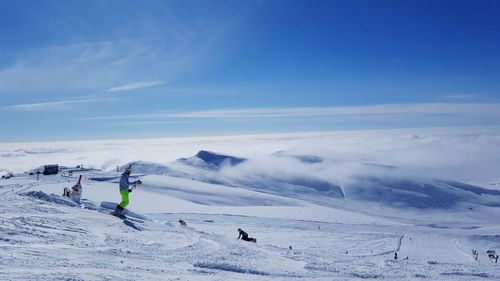 People skiing on snowcapped mountain against sky