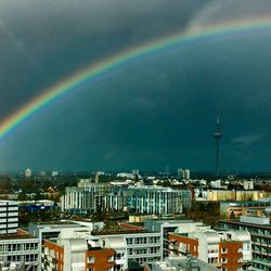 Rainbow over cityscape against sky