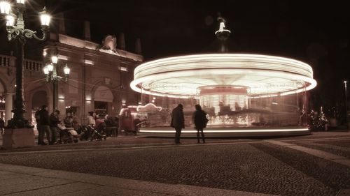 People standing on illuminated street at night