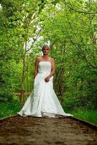 Portrait of woman with umbrella standing against trees