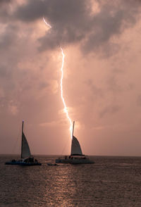 Sailboat in sea against sky during sunset with lightning 
