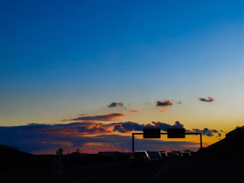 Cars on road against sky during sunset