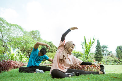 People sitting by plants against sky