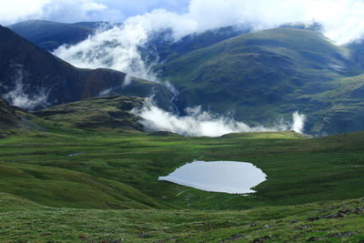 Lake in the alpine valley of the karagem pass on adtay at sunrise with clouds in the sunlight,summer