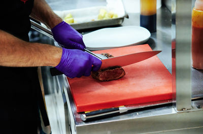 Midsection of man slicing food in restaurant kitchen