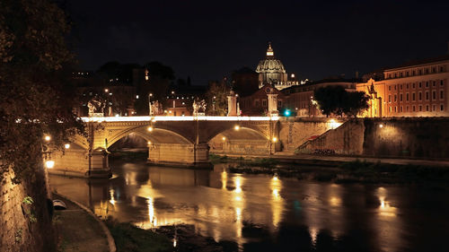 Illuminated bridge over river at night