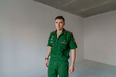 Portrait of soldier standing against wall