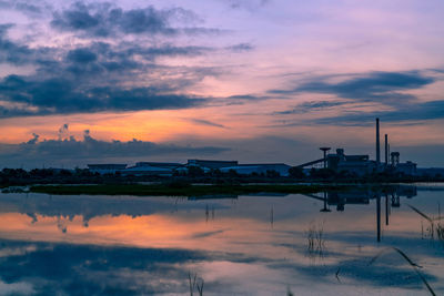 Landscape of factory industry buildings with dark blue and orange sunset sky reflection.