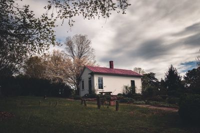 House on field by trees against sky
