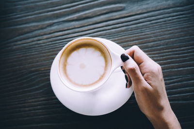 High angle view of woman holding coffee cup on table