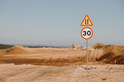 Road sign in desert against clear sky