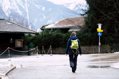 Rear view of man walking on mountain against buildings