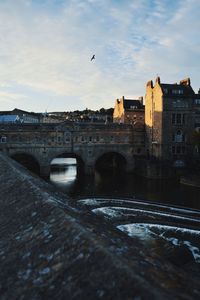 Arch bridge over river against buildings in city