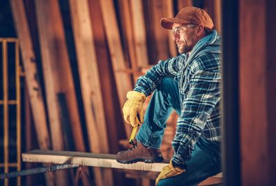 Side view of worker sitting at construction site while looking away