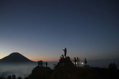 Silhouette people on mountain against clear sky
