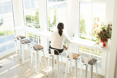 Rear view of woman sitting on table