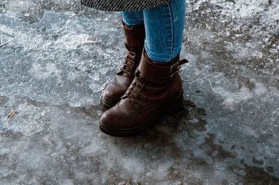 Low section of woman wearing boot while standing on road