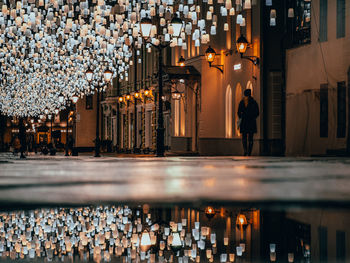 Rear view of people walking on illuminated street at night