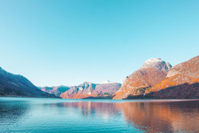 Scenic view of lake and mountains against clear blue sky