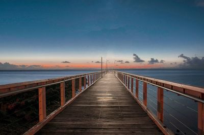 Pier on sea against sky during sunset