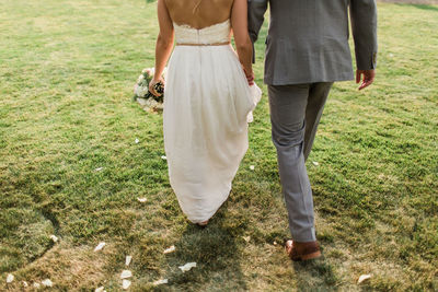 Rear view of couple walking on field