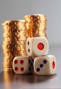 Close-up of stacked coins with dice against black background