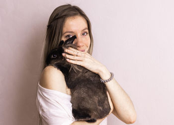 Portrait of young woman with dog against white background