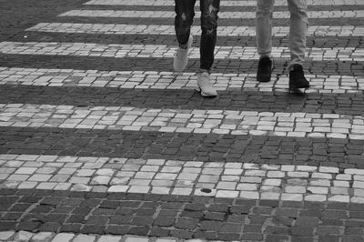 Low section of people walking on cobblestone street