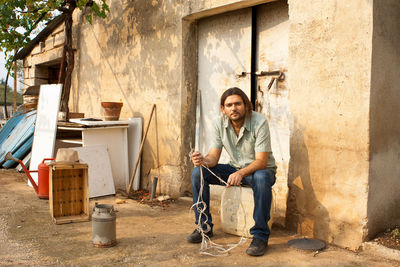 Portrait of man sitting on can