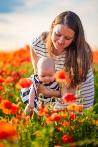 Mother with girl touching flowers in park